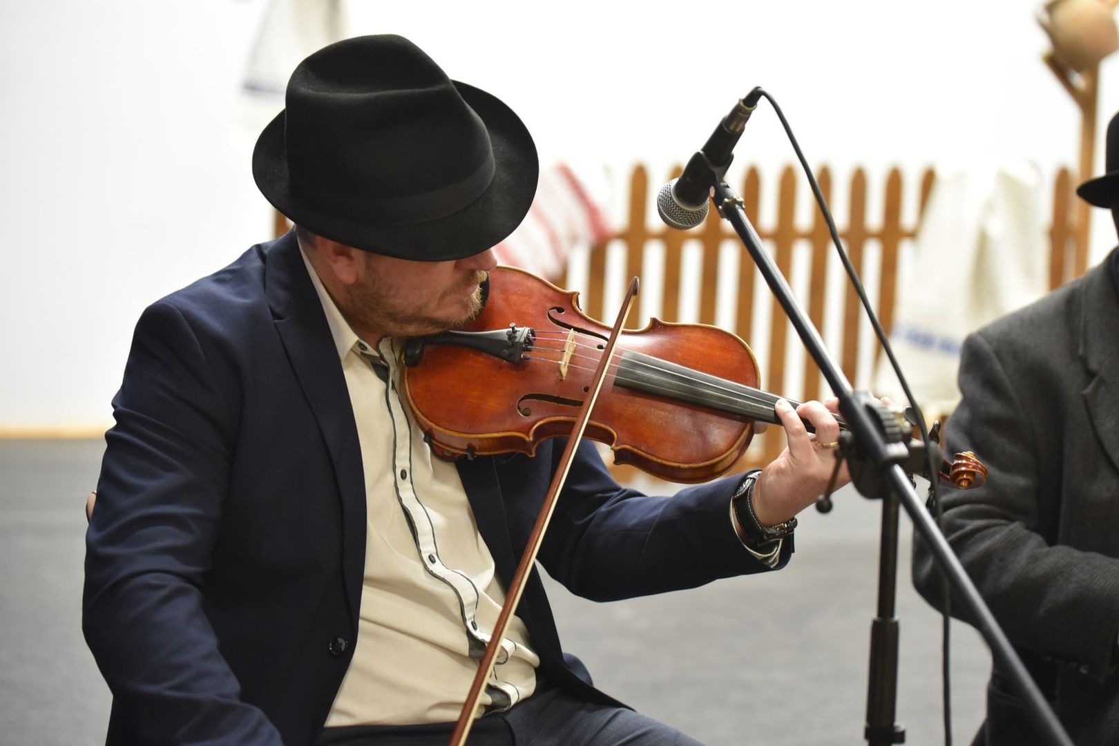 Fiddler in a black hat performing beside a microphone