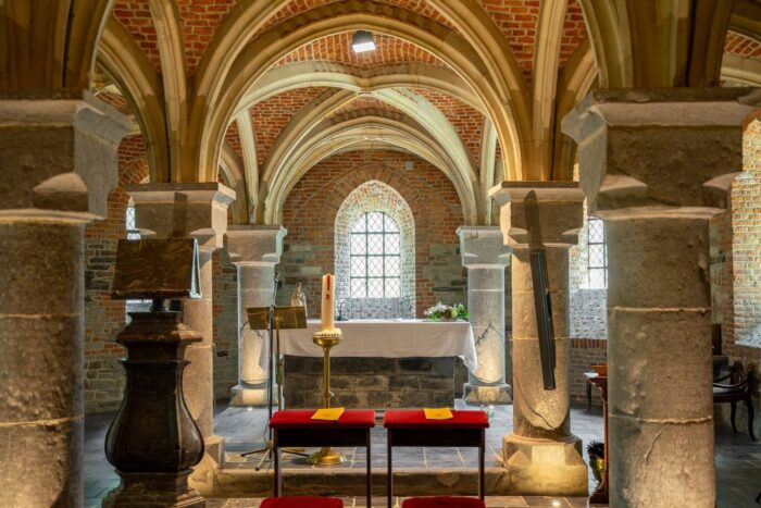 Historic brick-and-stone chapel interior with vaulted arches and altar