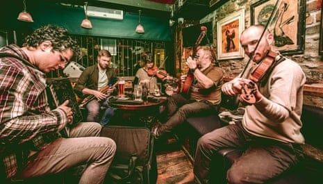 Folk musicians playing instruments together in a warmly lit pub